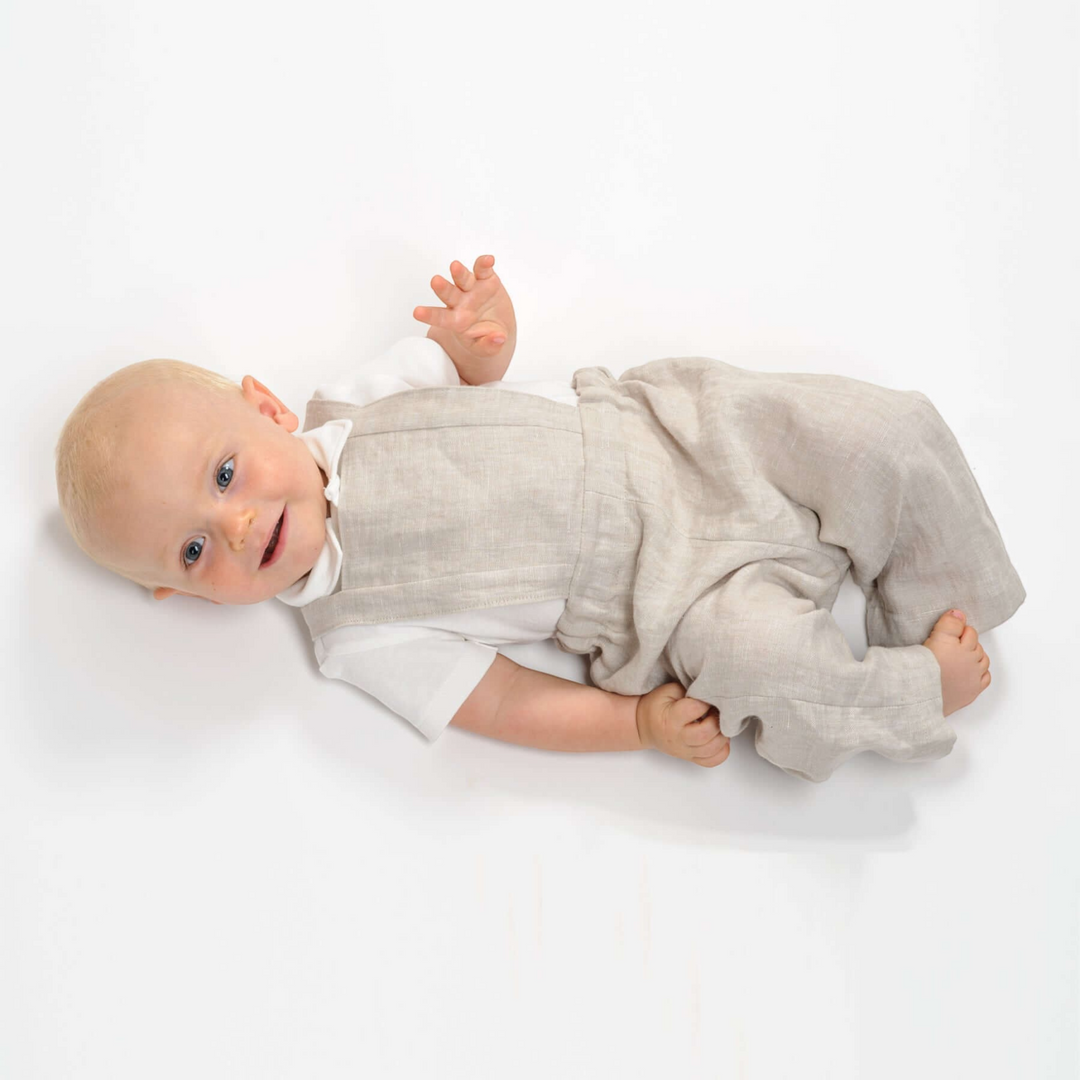 Patternforkids Kleinkind Latzhose MAX aus beigem Leinen, getragen von einem Baby auf weißem Hintergrund
