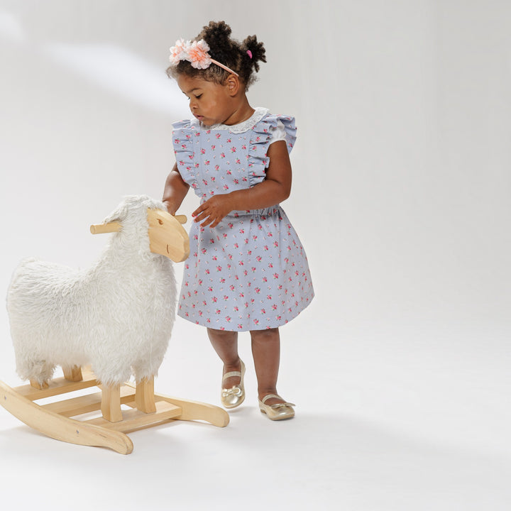 Latzkleid PDF Schnittmuster LIVIA – Rüschenkleid mit Trägern 68/74–116/122, kleines Mädchen im Rüschenkleid mit Spielzeug-Schaf.