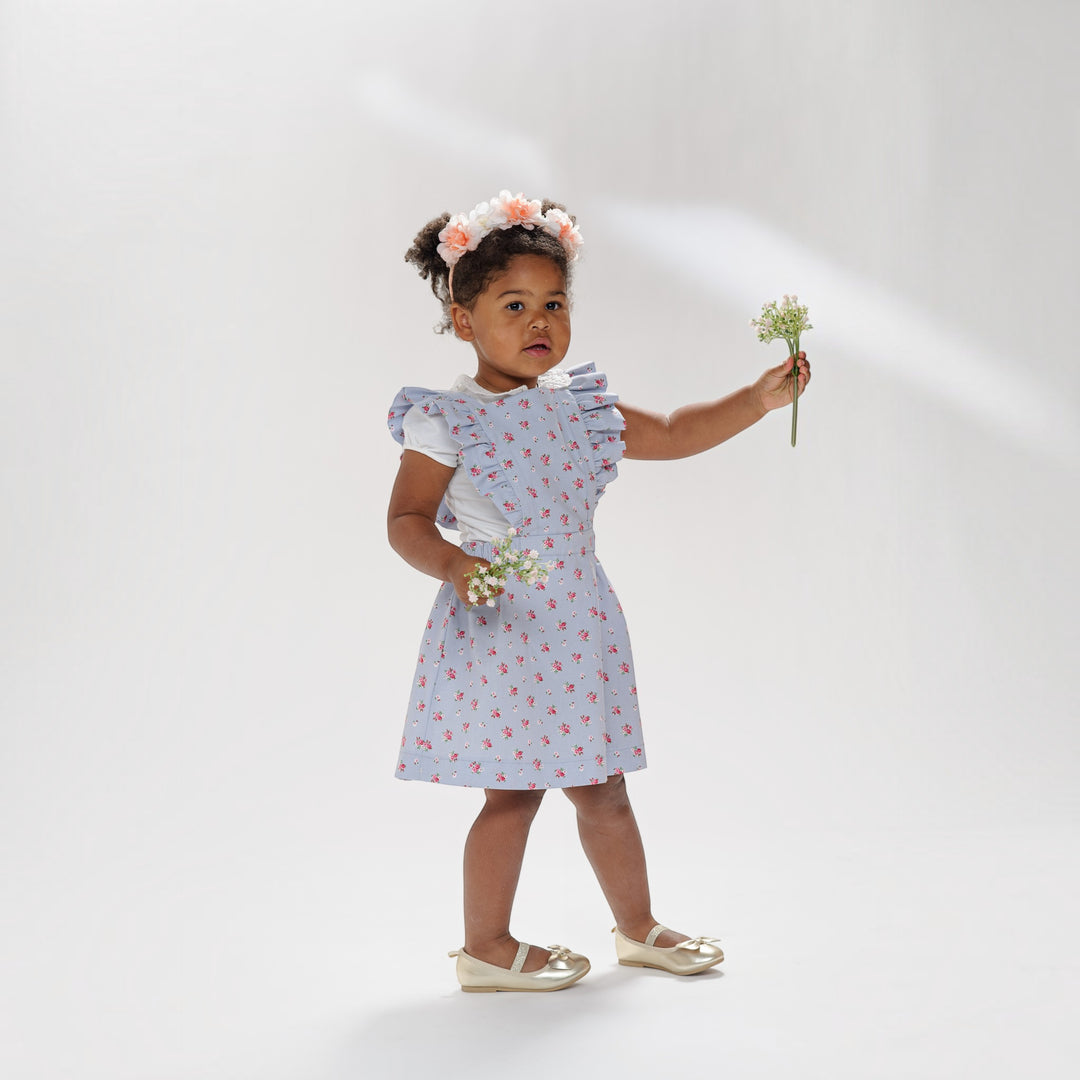 Latzkleid PDF Schnittmuster LIVIA – Rüschenkleid mit Trägern 68/74–116/122, babygirl in floral dress holding flowers.