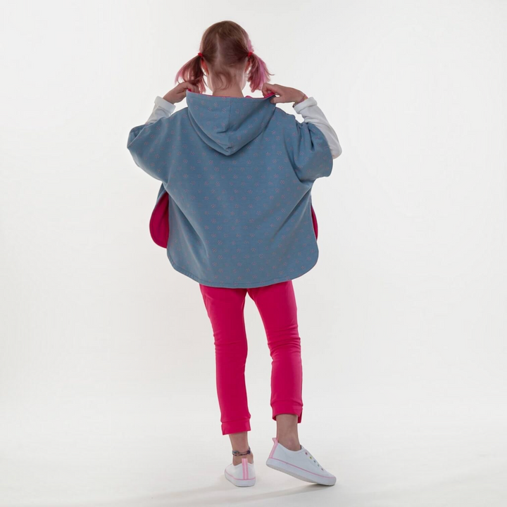 Patternforkids Schnittmuster Mädchen Poncho PAULA mit Kapuze, blau gemustert, von hinten auf einem Kind
