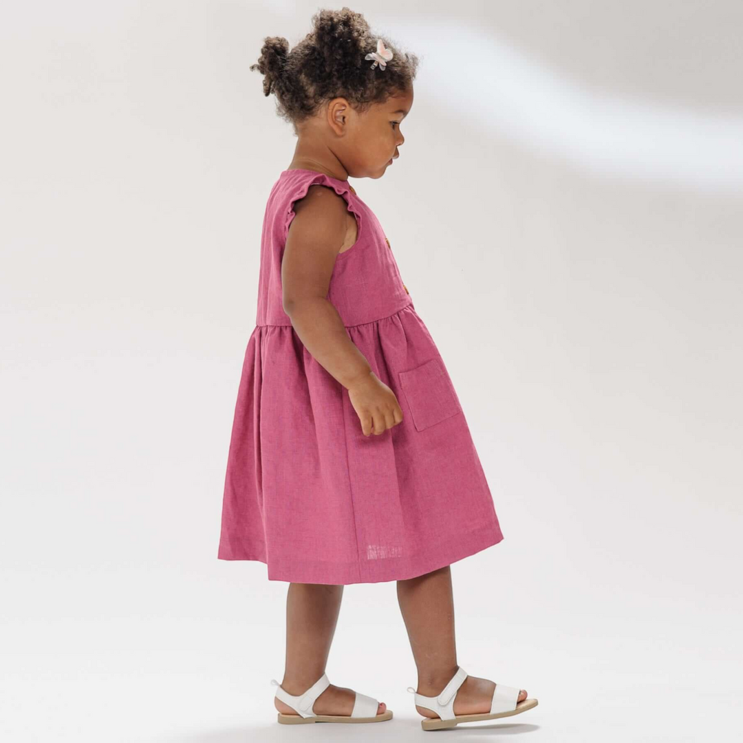 Patternforkids Mädchenkleid MIMI in Pink mit Rüschenärmeln und aufgesetzten Taschen an einem kleinen Mädchen
