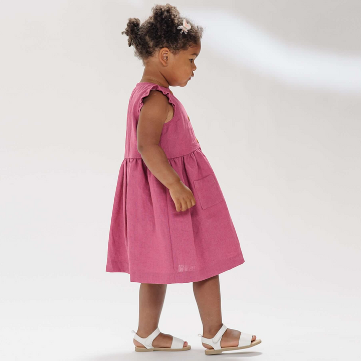 Patternforkids Mädchenkleid MIMI in Pink mit Rüschenärmeln und aufgesetzten Taschen an einem kleinen Mädchen