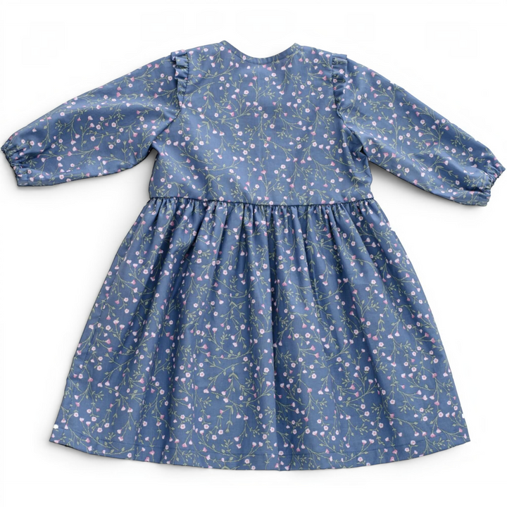 Patternforkids Mädchenkleid MIMI Schnittmuster mit blauem Blumenmuster, Langarm und Rüschen an den Schultern.
