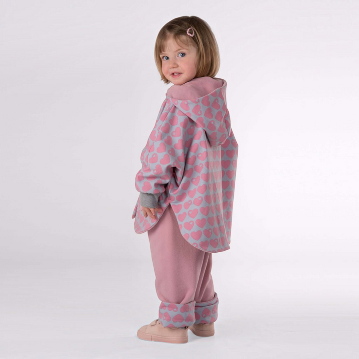 Patternforkids Schnittmuster Set MARA FIOCCO: Kind trägt wendbaren Poncho mit Herzmuster und passende gefütterte Hose