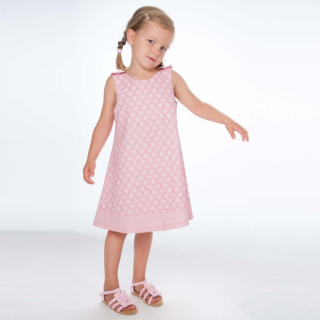 Mädchen trägt ein rosa A-Linien Kleid mit Blumenmuster von Patternforkids, kombiniert mit passenden Sandalen.