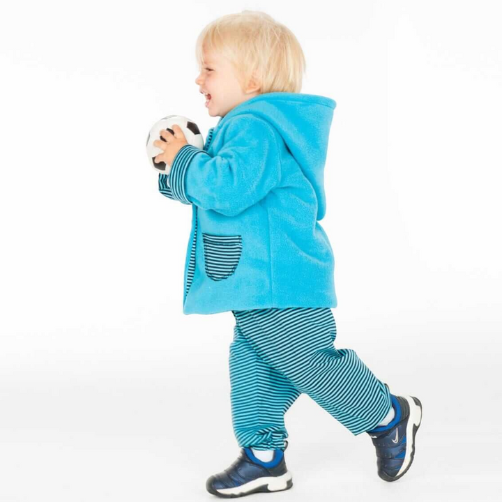 Patternforkids Schnittmuster Set TORETTO TORINO: Kind trägt blaue Kapuzenjacke und gestreifte Hose beim Spielen