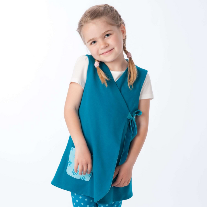 Patternforkids LENA ENNA Schnittmuster Set: Mädchen trägt eine petrolfarbene Tunika mit Wickeloptik und gepunktete Leggings.