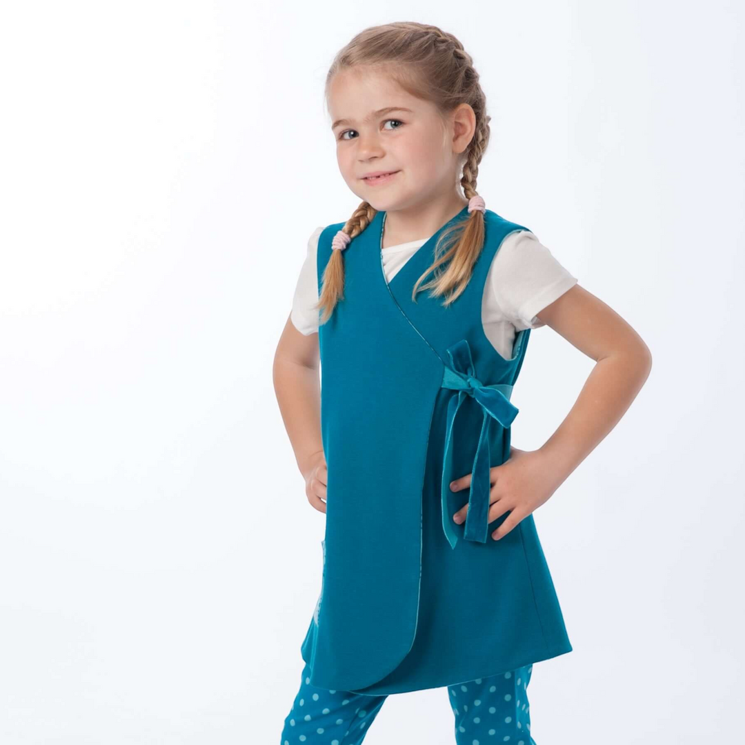 Patternforkids Schnittmuster LENA ENNA: Mädchen trägt eine petrolfarbene Wickeltunika und gepunktete Leggings.