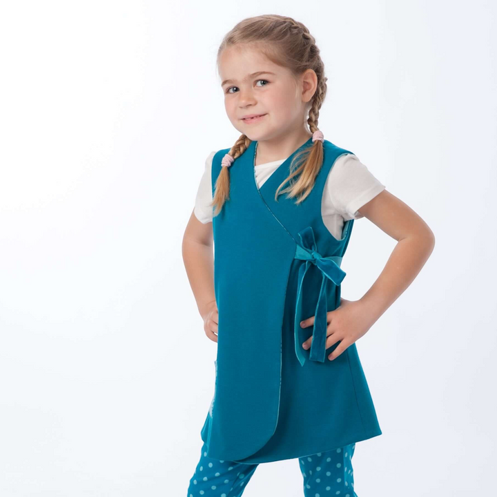 Patternforkids Schnittmuster LENA ENNA: Mädchen trägt eine petrolfarbene Wickeltunika und gepunktete Leggings.