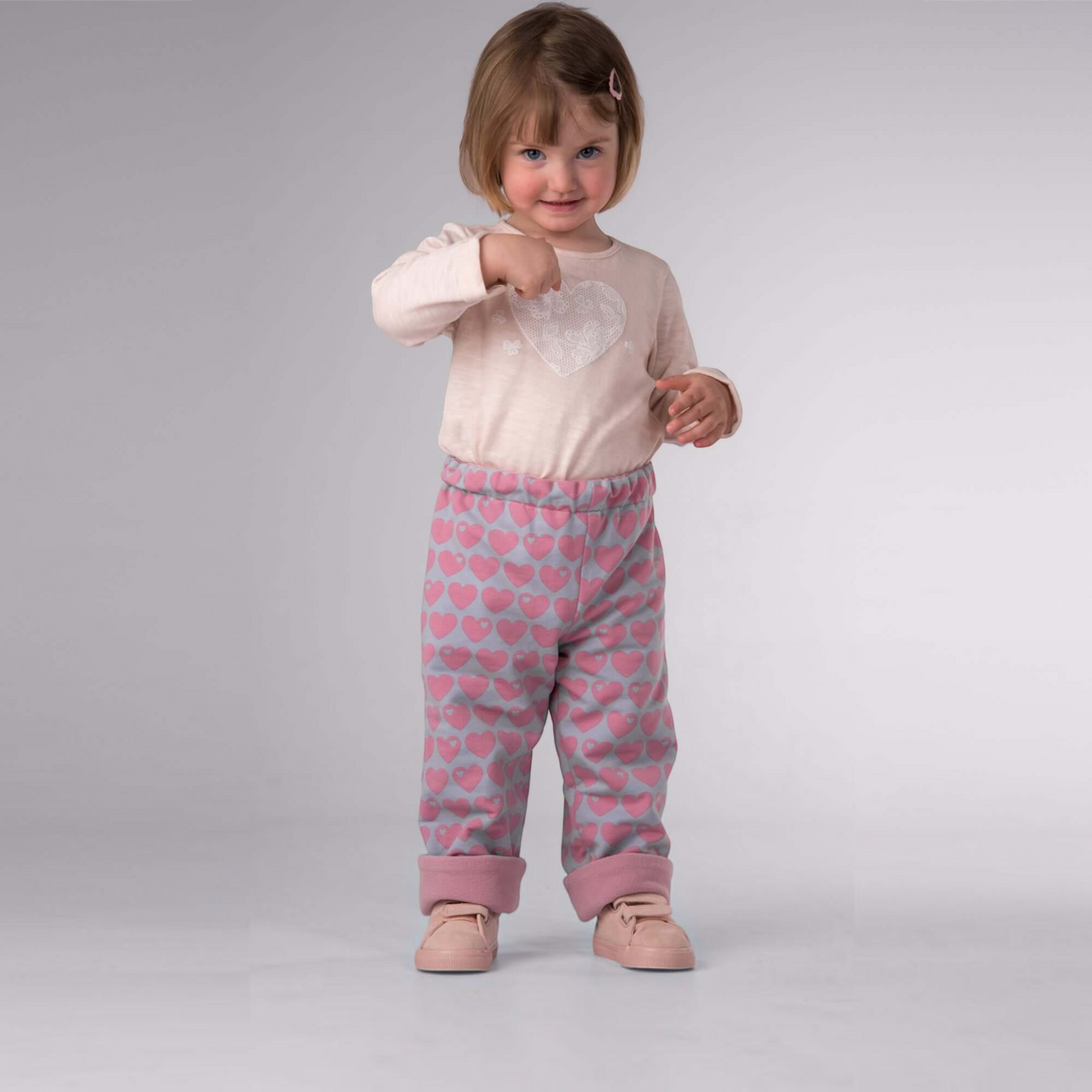 Patternforkids Wendehose FIOCCO mit rosa Herzmuster und umgeschlagenem Saum an einem kleinen Mädchen