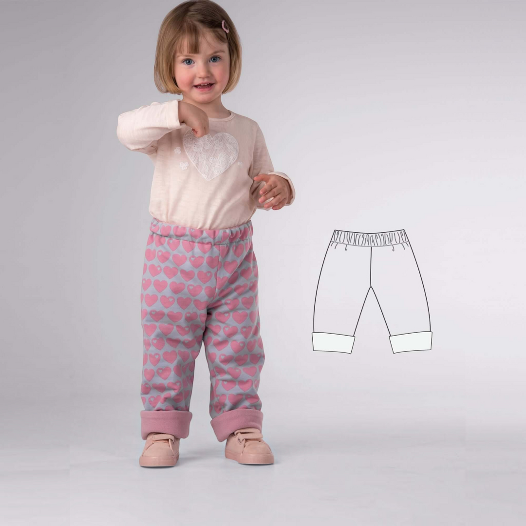 Patternforkids Schnittmuster Set MARA FIOCCO: Kind trägt eine graue Wendehose mit rosa Herzmuster und umgeschlagenem Saum.