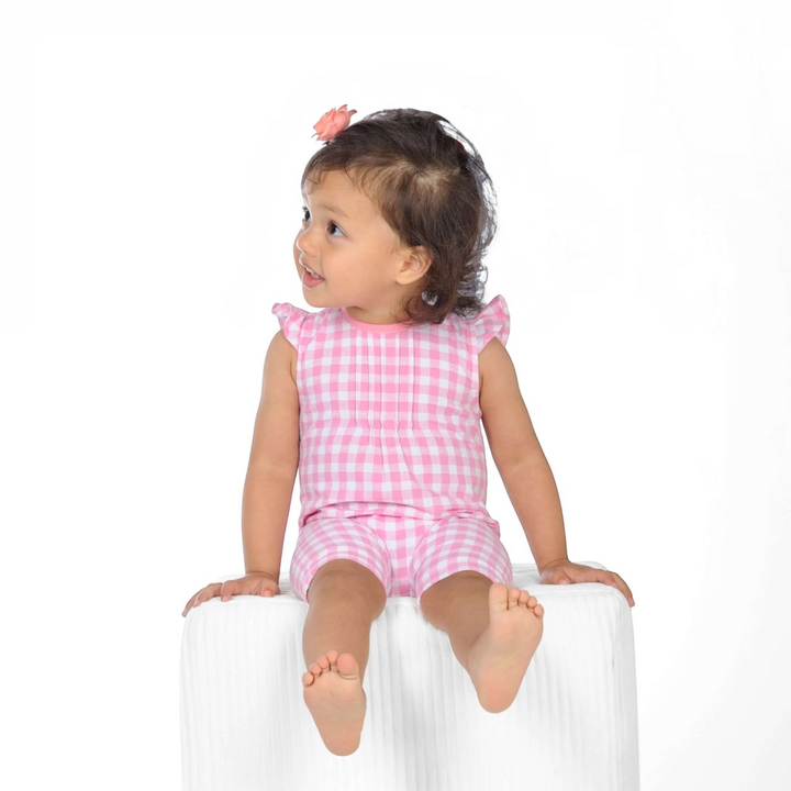 Schnittmuster Baby Overall MIA PDF auf einem süßen Kind in einem karierten Overall mit Rüschenaermeln.