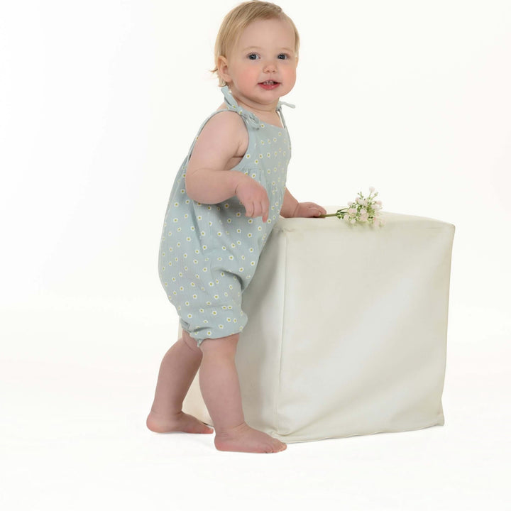 Schnittmuster Baby Mädchen Jumpsuit NELE PDF - Kind im blauen Overall mit Blumenmuster, mit weißem Hintergrund.