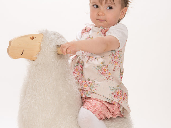 Schnittmuster Baby Twinset Babykleid Hängerchen und Pumphose - Baby sitzt auf einem Plüschtier.