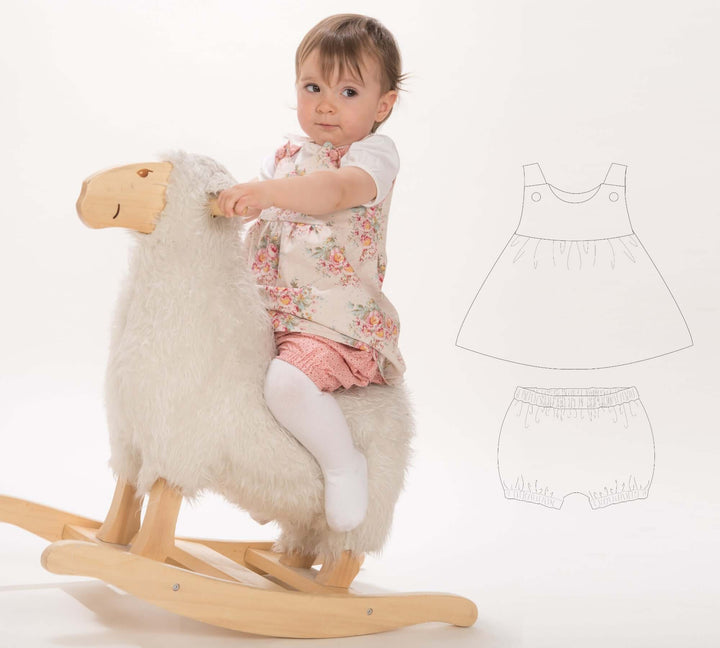 Schnittmuster Baby Twinset Babykleid Hängerchen und Pumphose CLARA EMI mit einem Mädchen auf einem Schaukel-Schaf.