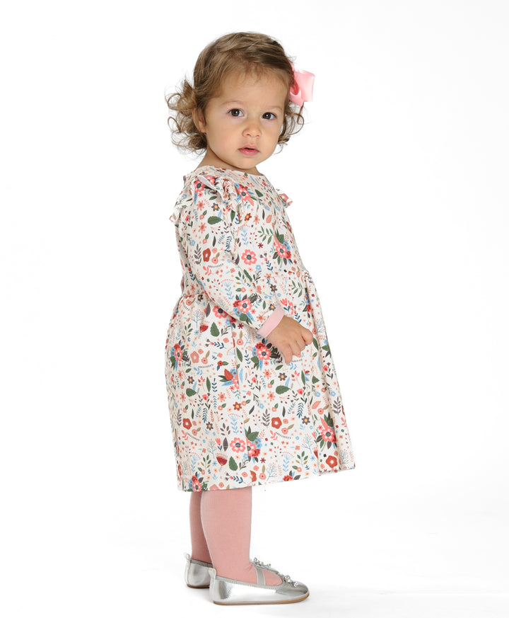 Schnittmuster Retro Kleid für Mädchen ELLA mit langen Ärmeln, gezeigt an einem Mädchen mit Blumenmuster.