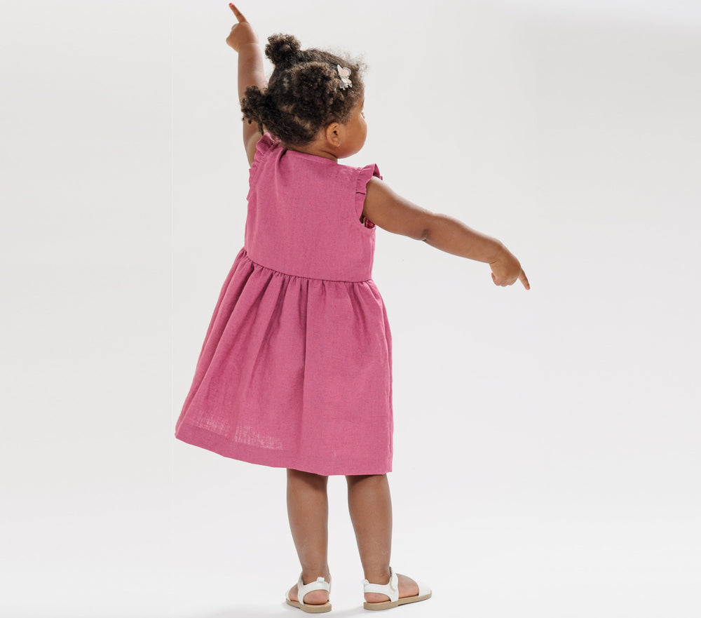 Schnittmuster Sommer Mädchenkleid MIMI in Rosa, langärmeliges Design für Kinder Gr. 6M–7J, Mädchen zeigt das Kleid von hinten.
