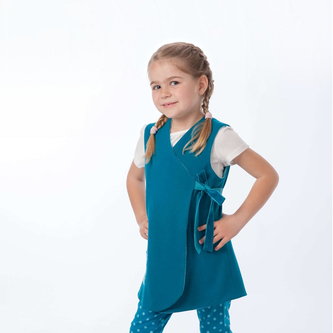 Mädchen trägt ein Wickelkleid aus dem Schnittmuster MARIE PDF in teal mit Schleife – 3 Varianten 92/98–128/134.