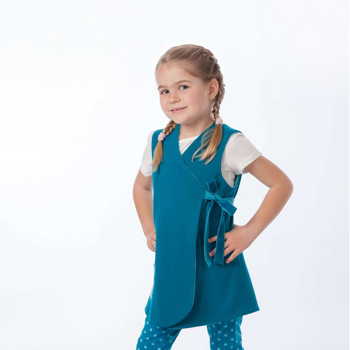 Mädchen trägt ein Wickelkleid aus dem Schnittmuster MARIE PDF in teal mit Schleife – 3 Varianten 92/98–128/134.